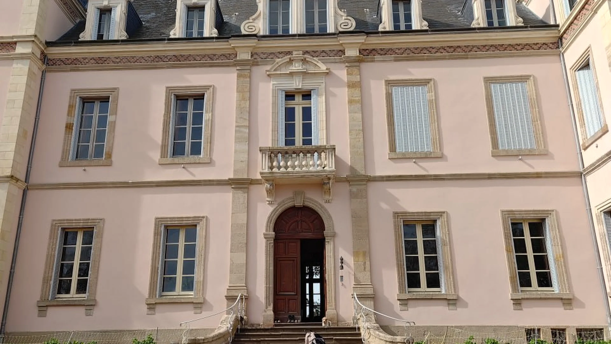 The château's daytime facade, seen down the length of the tree-lined avenue