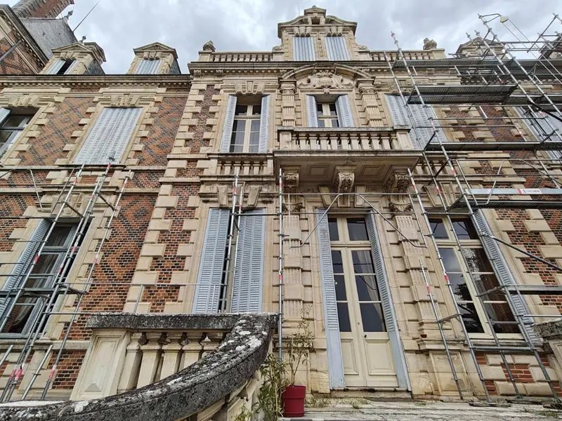 Wrought-iron balcony and carved stone detailing on the brick facade