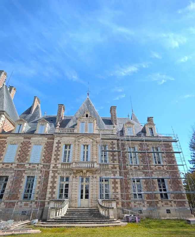 The full brick-and-stone facade beneath dramatic cloud