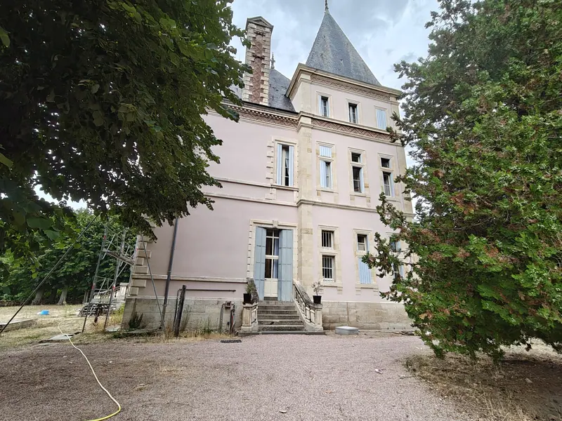 The chateau glimpsed through heavy summer foliage