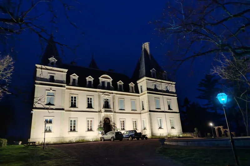 The chateau lit from below against a deep blue evening sky