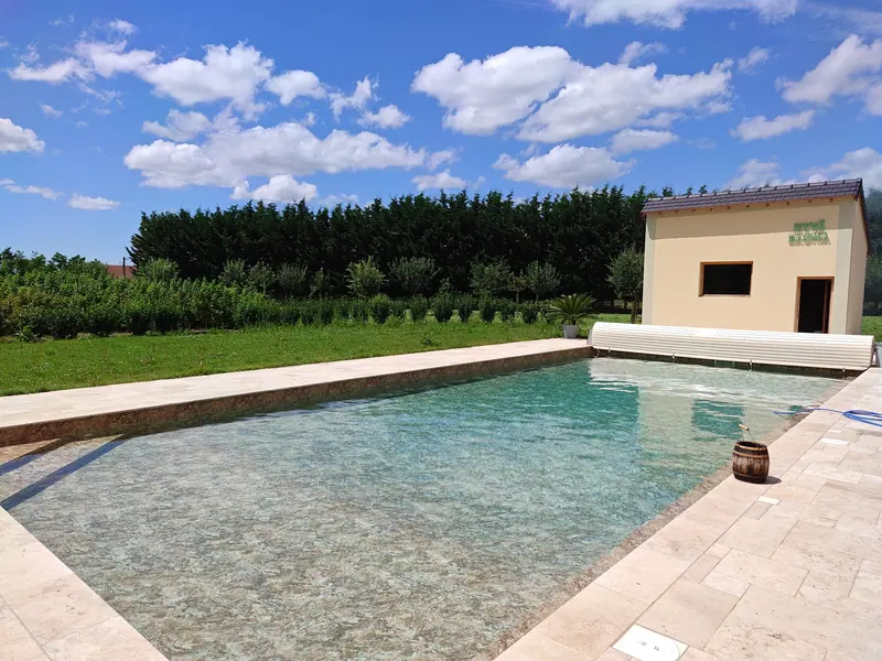 The pool and pool house enclosed by clipped hedging under a summer sky